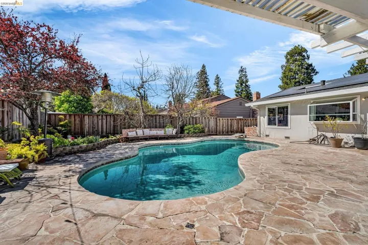 View of swimming pool featuring a fenced backyard, patio surround, and a pergola