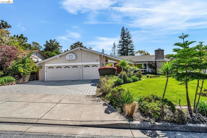 Ranch-style house with concrete driveway, an attached garage, a front lawn, a chimney, and board and batten siding