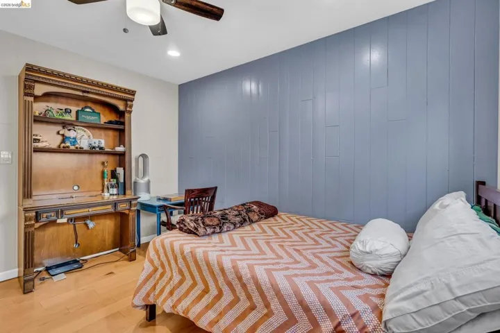 Bedroom featuring wood walls, light wood-style flooring, recessed lighting, and ceiling fan