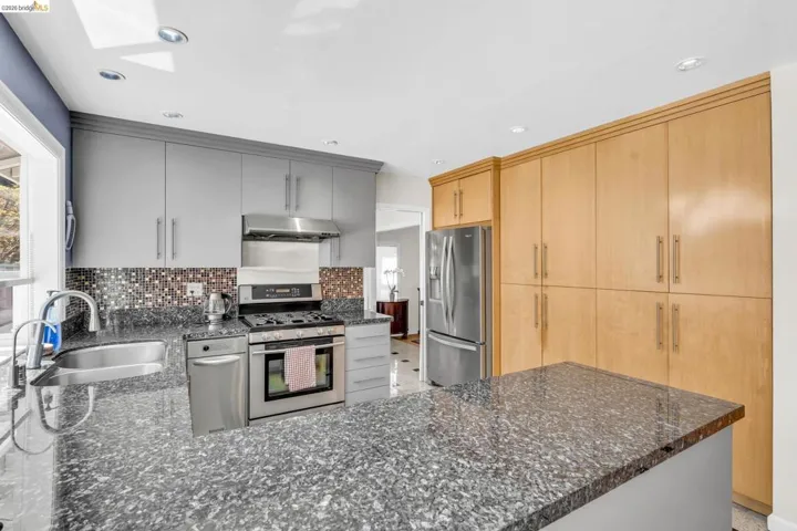 Kitchen featuring stainless steel appliances, dark stone counters, a peninsula, gray cabinetry, and recessed lighting
