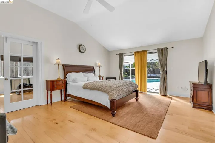 Bedroom with vaulted ceiling, light wood-style floors, access to outside, and a ceiling fan