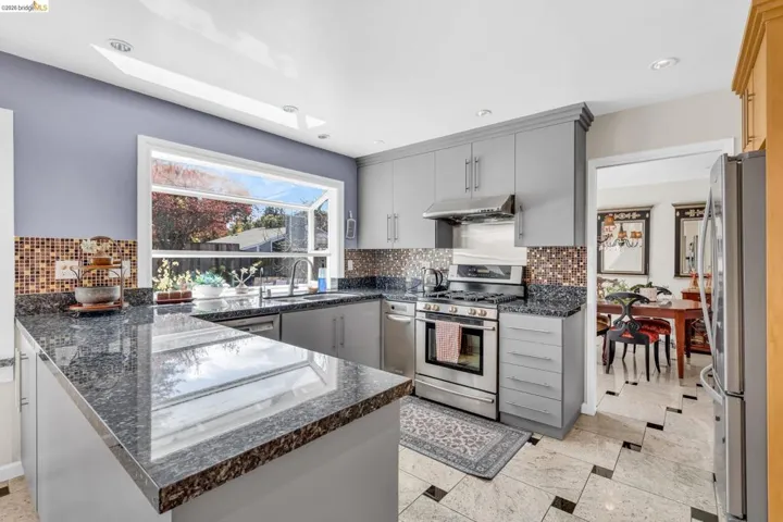 Kitchen with gray cabinets, stainless steel appliances, a skylight, a peninsula, and recessed lighting