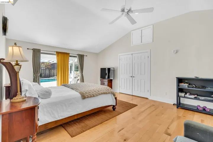 Bedroom with access to exterior, lofted ceiling, light wood-style flooring, a ceiling fan, and a closet