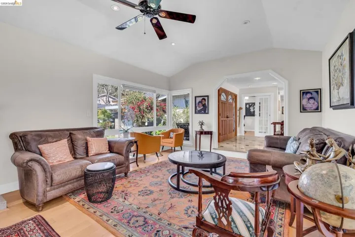 Living area with arched walkways, lofted ceiling, recessed lighting, ceiling fan, and light wood-style floors