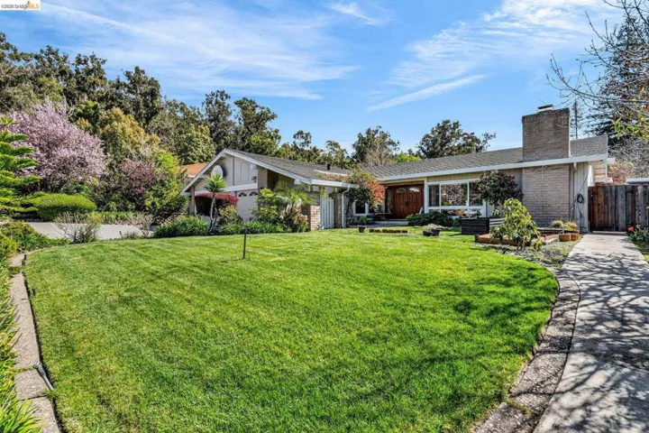 View of front facade featuring a chimney, brick siding, a shingled roof, and board and batten siding