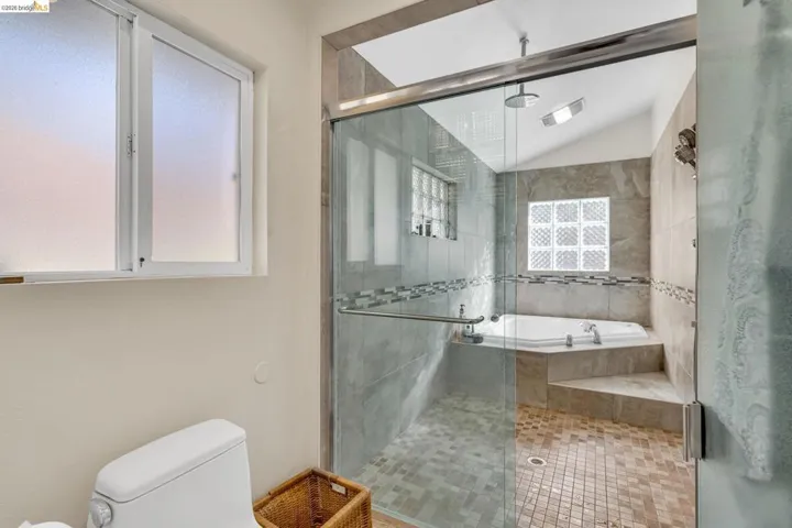 Full bathroom with a shower stall, lofted ceiling, and a bath