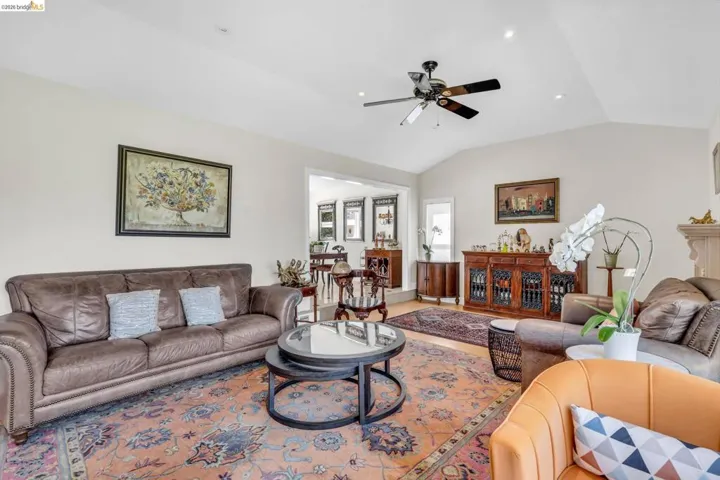 Living room with a ceiling fan, lofted ceiling, and recessed lighting