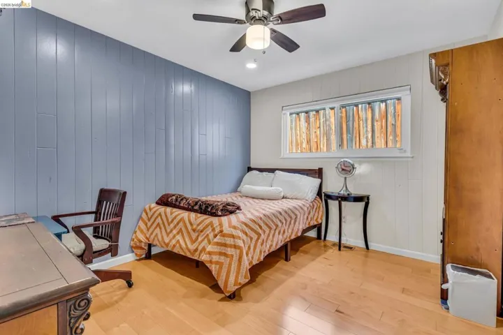 Bedroom with wood walls, light wood-style flooring, a ceiling fan, and recessed lighting