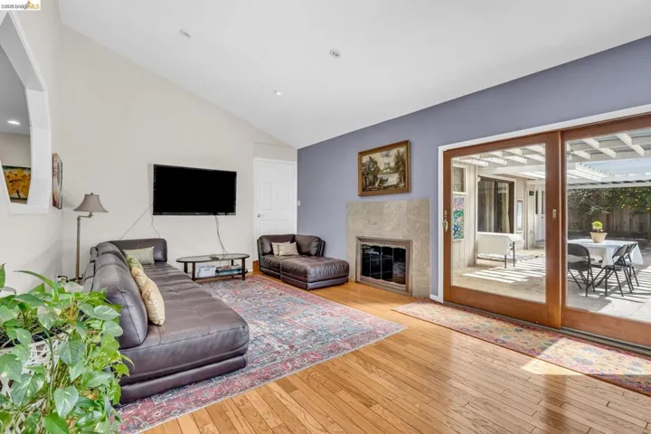 Living area featuring a fireplace, light wood-type flooring, and vaulted ceiling