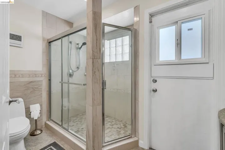 Full bathroom featuring a shower stall, tile walls, and vanity