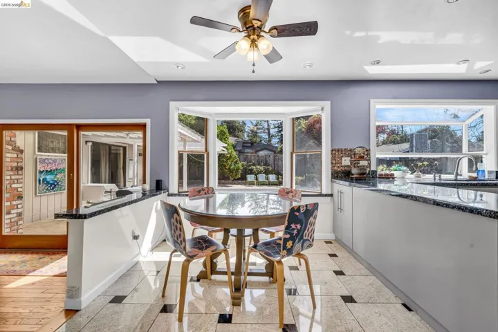 Dining area featuring granite tiled floors, a skylight, inlaid floor details, and ceiling fan