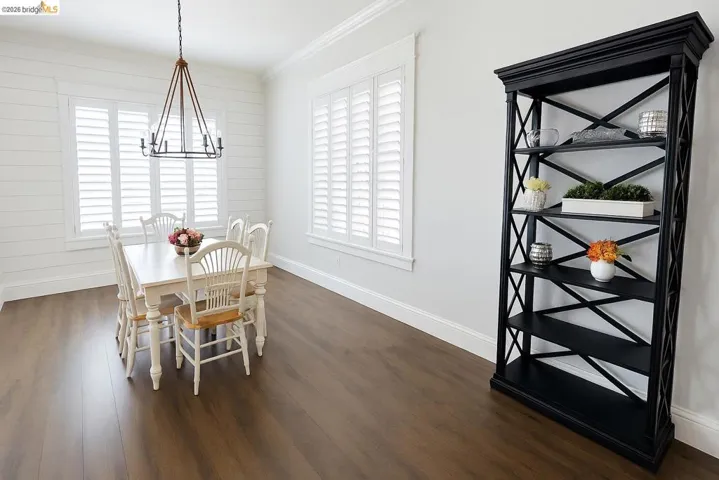 Dining room featuring dark wood-style flooring, a chandelier, and ornamental molding