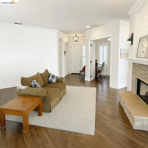 Living room featuring a desk, dark wood-style floors, ornamental molding, arched walkways, and a fireplace