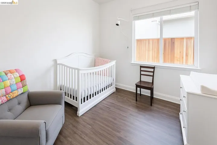 Bedroom with dark wood finished floors and a crib