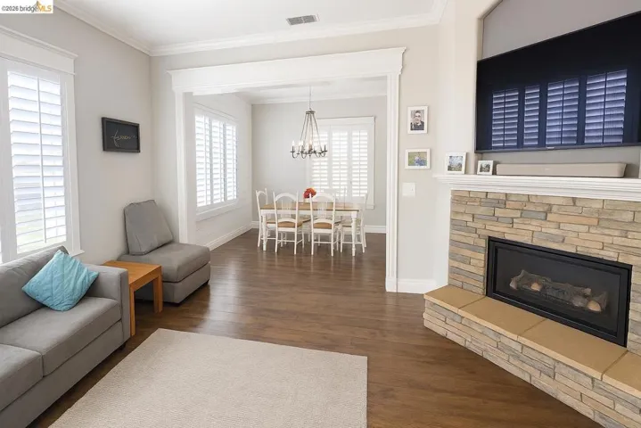 Living area with crown molding, a fireplace, dark wood-type flooring, and a chandelier