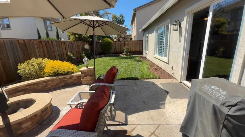 Fenced backyard featuring a patio, grilling area, and a fire pit