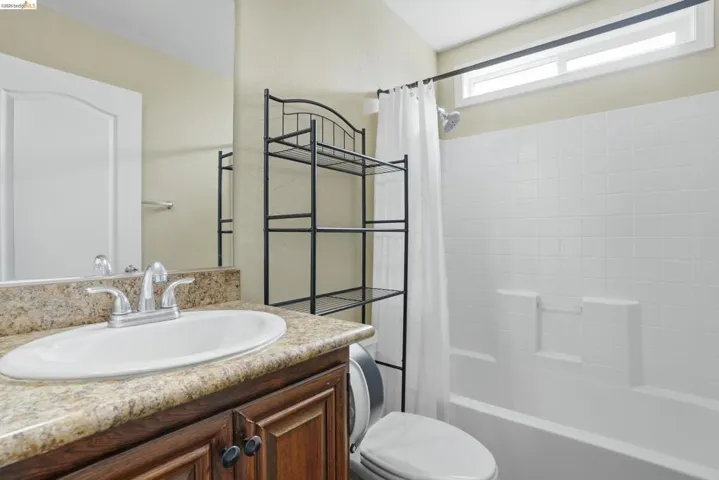 Full bathroom with shower / bath combo with shower curtain, vanity, and a textured wall