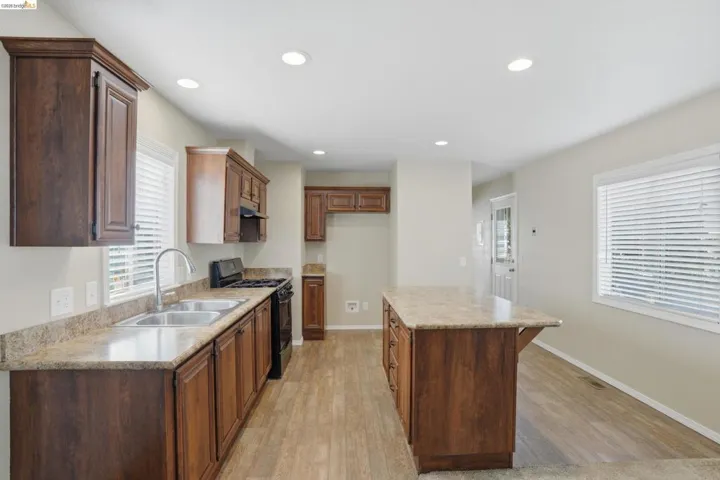 Kitchen with gas stove, a center island, recessed lighting, light wood-type flooring, and wood finish cabinets