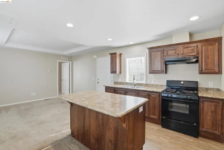 Kitchen with black gas range, a breakfast bar area, light countertops, a center island, and light wood-style flooring