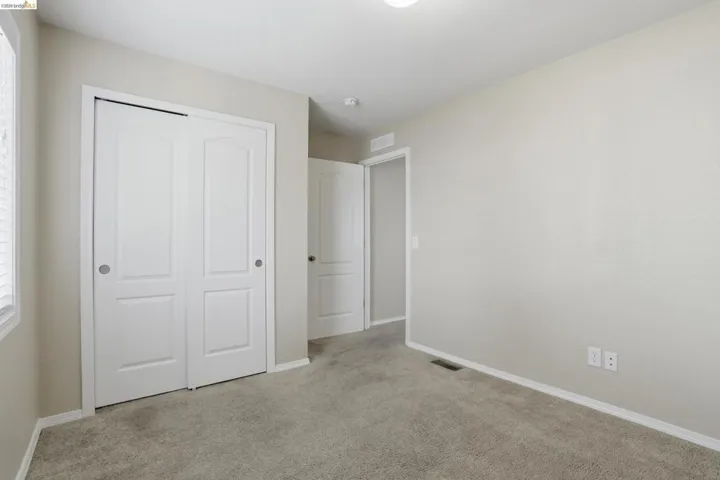 Unfurnished bedroom featuring light carpet and a closet
