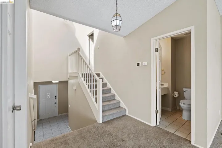 Staircase featuring carpet floors, tile patterned floors, and a textured ceiling