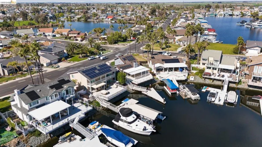 Aerial view of property and surrounding area featuring a nearby body of water and nearby suburban area