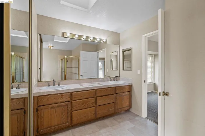 Bathroom featuring double vanity, a skylight, and a stall shower