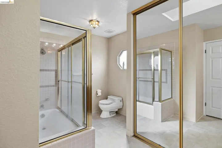 Full bathroom featuring a bath, a shower stall, and a textured wall