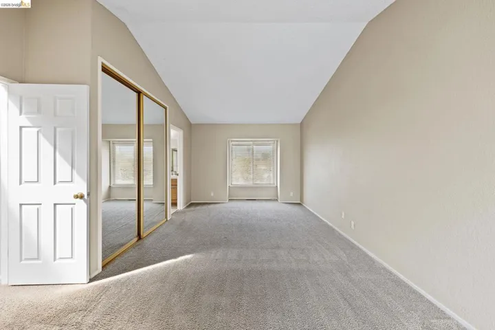 Unfurnished room featuring carpet and lofted ceiling