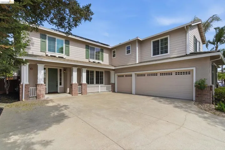 View of front of property featuring brick siding, an attached garage, concrete driveway, and roof mounted solar panels