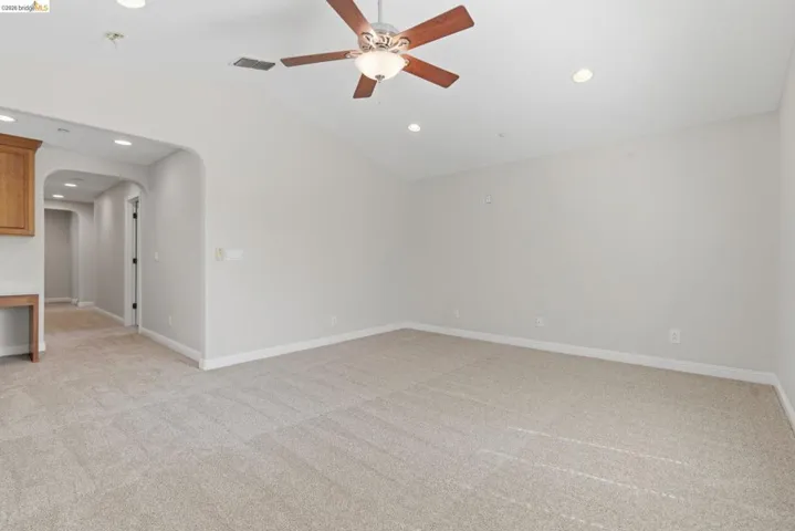 Unfurnished room with arched walkways, light carpet, a ceiling fan, vaulted ceiling, and recessed lighting