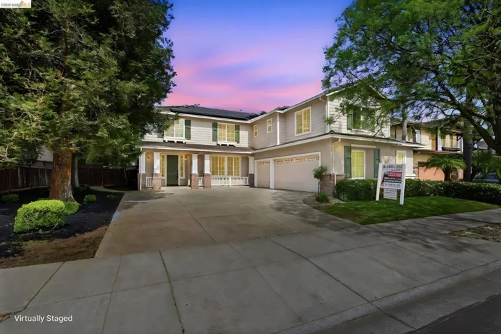 View of front of home with solar panels, an attached garage, driveway, brick siding, and a porch