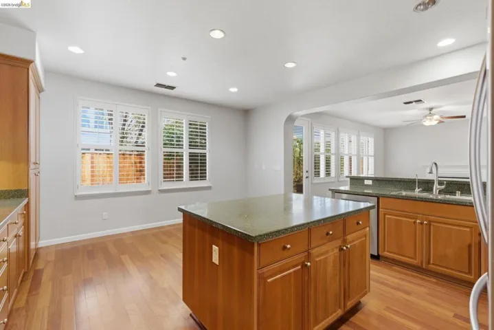 Kitchen featuring wood finish cabinetry, light wood-type flooring, a kitchen island, recessed lighting, and dark stone counters
