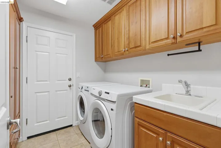 Laundry room featuring light tile patterned flooring, cabinet space, and washer and clothes dryer