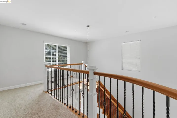 Hallway featuring light carpet and an upstairs landing