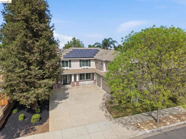 View of front of property with roof mounted solar panels, driveway, and an attached garage