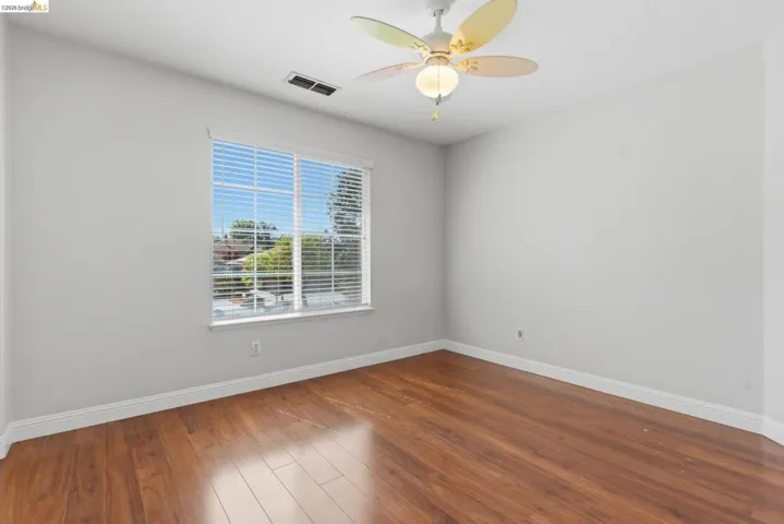 Unfurnished room with dark wood-style flooring and a ceiling fan