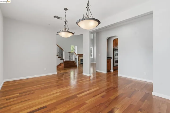 Unfurnished living room featuring arched walkways and light wood-type flooring
