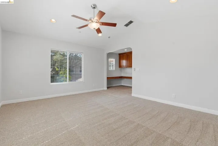 Empty room featuring arched walkways, light carpet, a ceiling fan, recessed lighting, and vaulted ceiling
