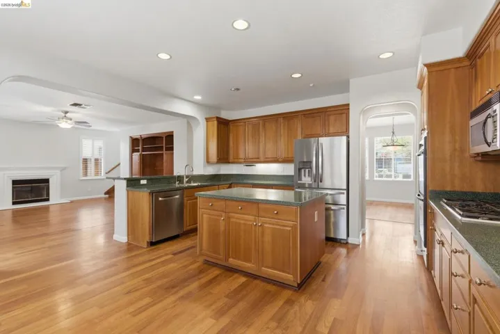 Kitchen with arched walkways, stainless steel appliances, ceiling fan, open floor plan, and recessed lighting