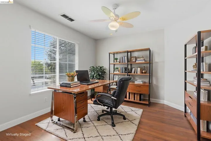 Office with dark wood-type flooring and a ceiling fan