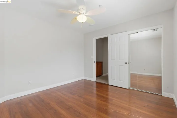 Unfurnished bedroom with dark wood-style flooring, ceiling fan, and a closet