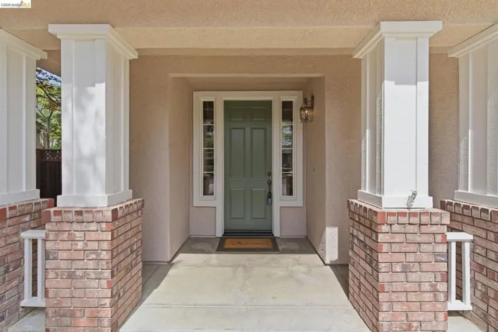 Property entrance with a porch, stucco siding, and brick siding