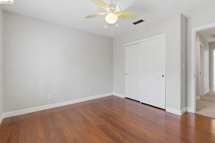 Unfurnished bedroom with a closet, ceiling fan, and dark wood-style flooring
