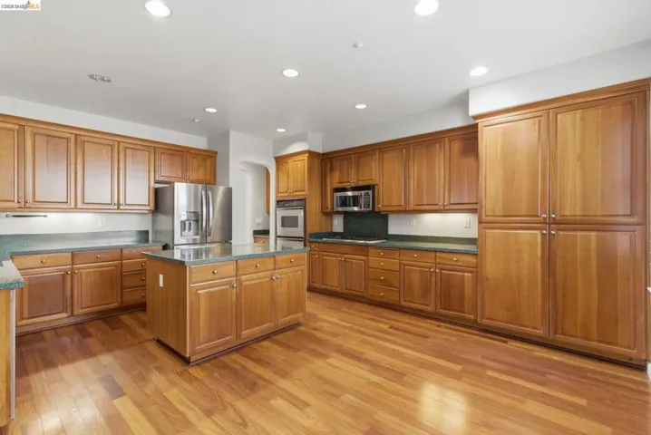 Kitchen with a kitchen island, stainless steel appliances, wood finish cabinets, light wood-style floors, and recessed lighting