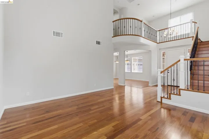 Unfurnished living room with plenty of natural light, a high ceiling, suspended lighting, wood finished floors, and arched walkways