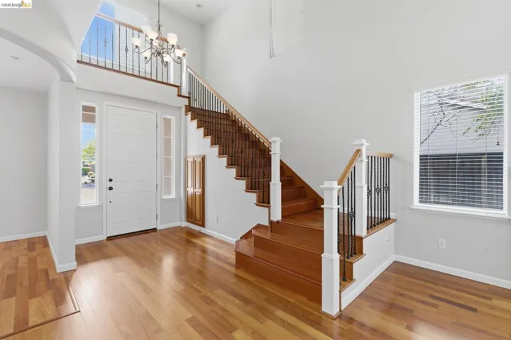 Entrance foyer with a high ceiling, light wood finished floors, a chandelier, and arched walkways