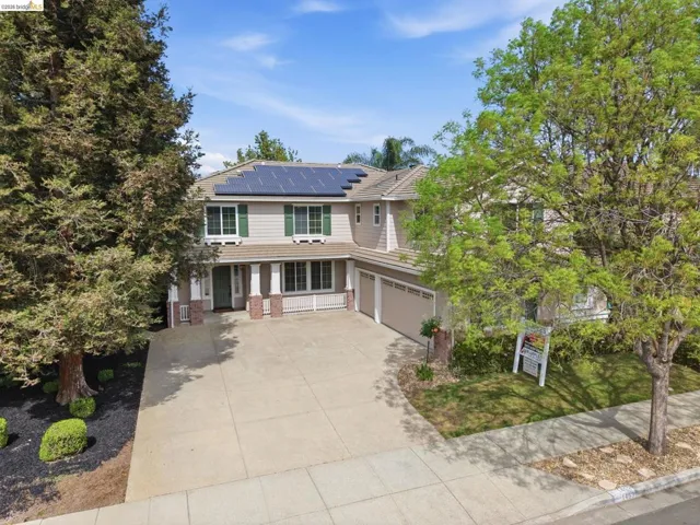 View of front of property featuring roof mounted solar panels, concrete driveway, brick siding, a garage, and a tile roof
