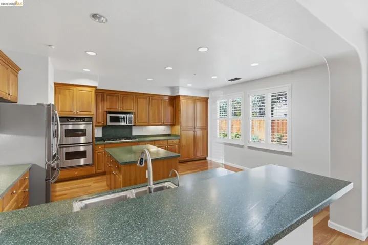 Kitchen featuring stainless steel appliances, a center island, wood finish cabinetry, light wood-style floors, and recessed lighting