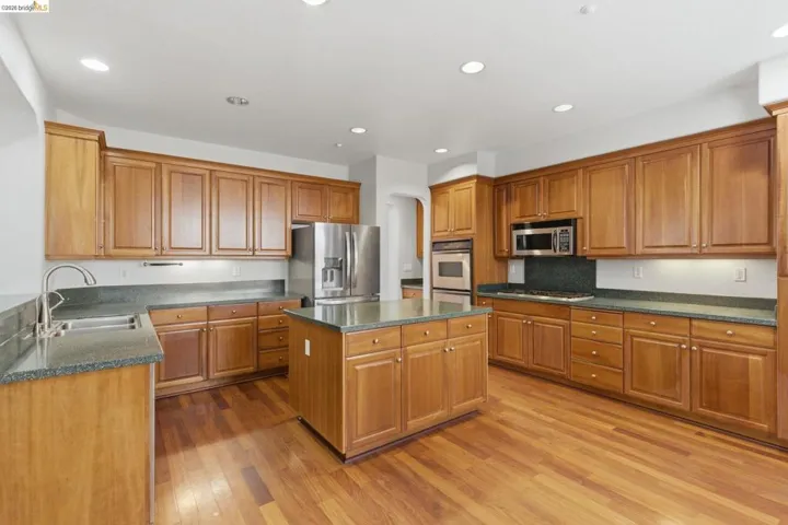 Kitchen with wood finish cabinetry, stainless steel appliances, light wood-style flooring, a center island, and recessed lighting